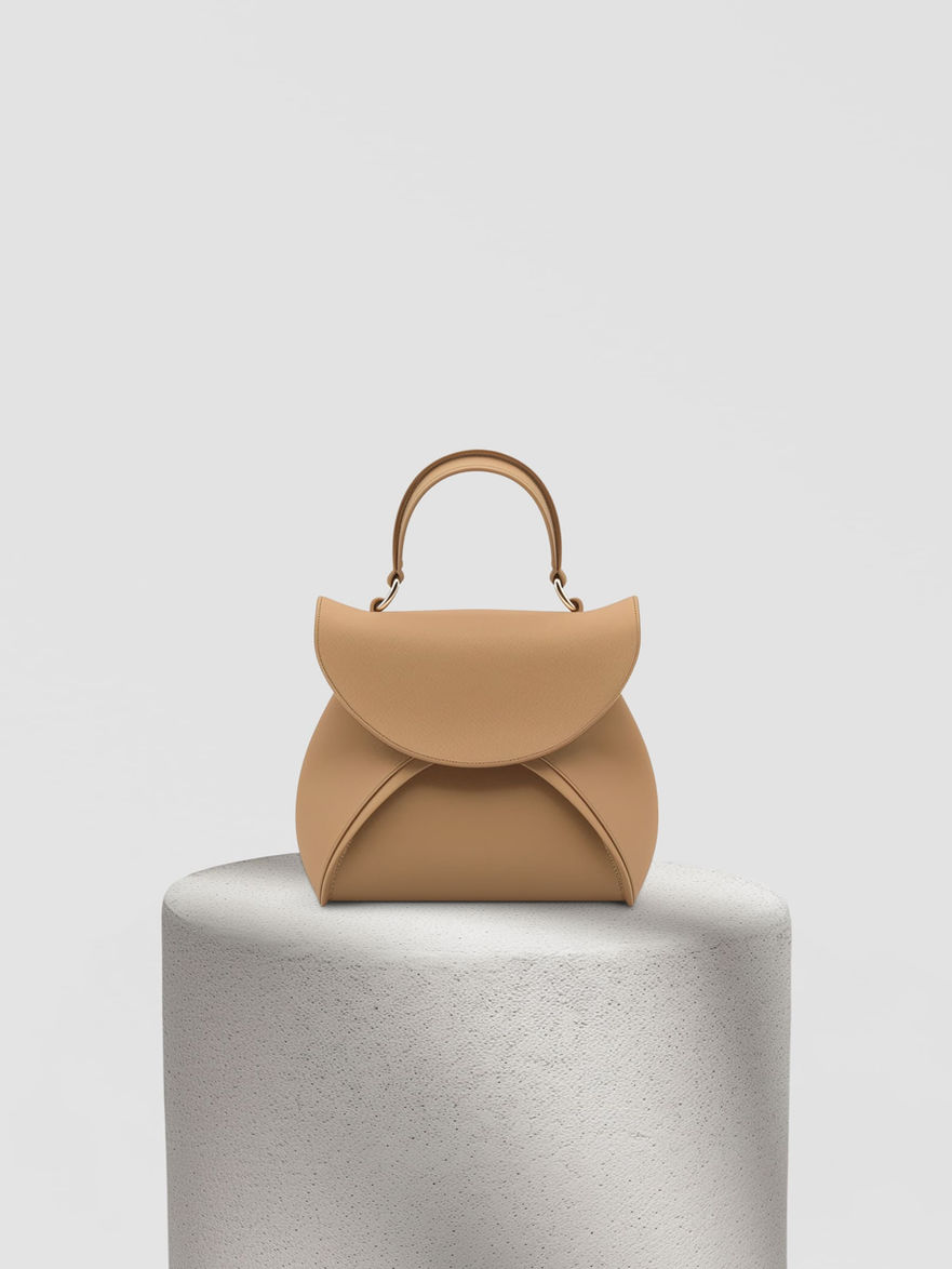 Tan leather handbag with a top handle displayed on a white pedestal