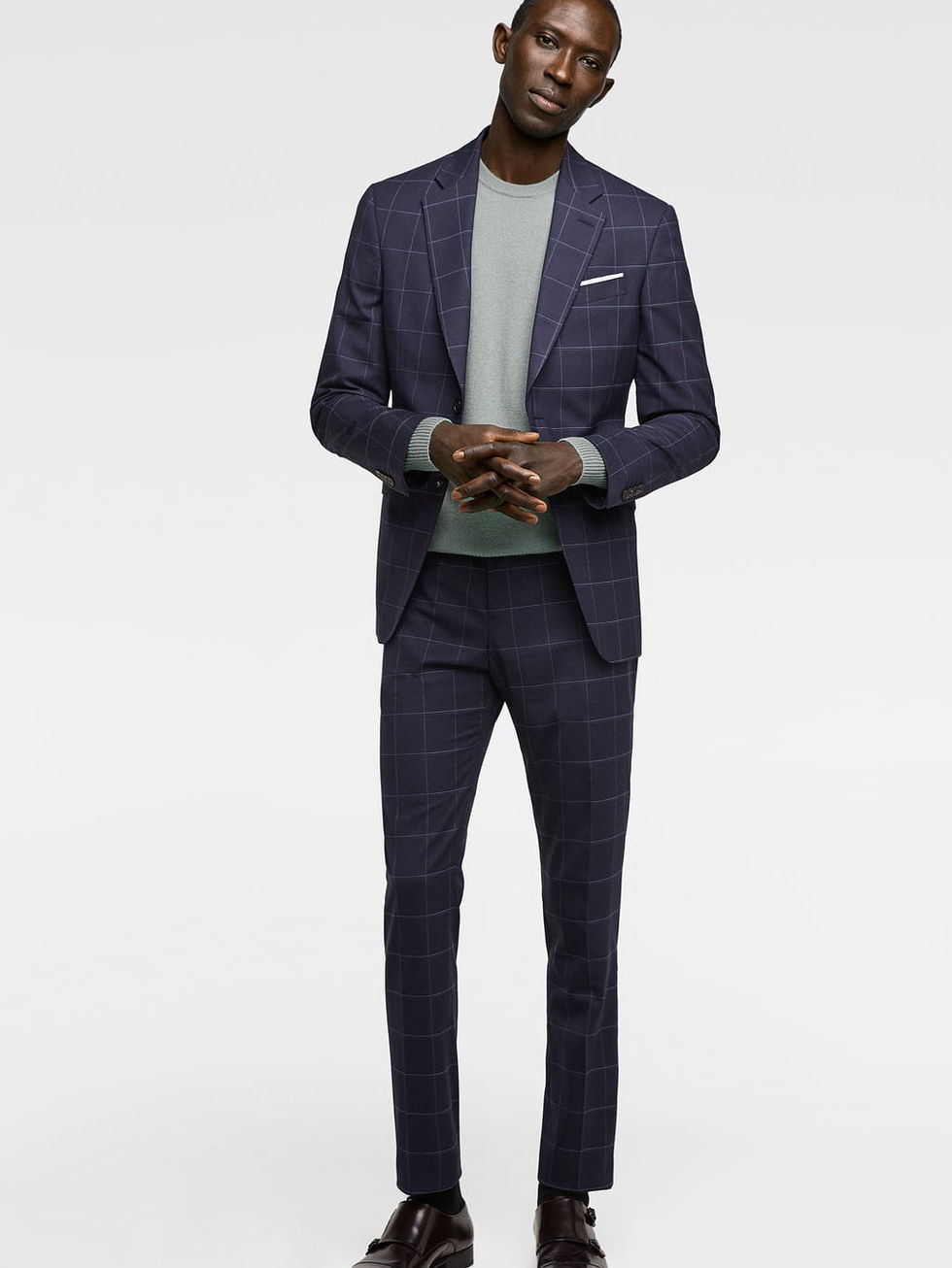 Man in a dark navy blue checkered suit with a light blue sweater