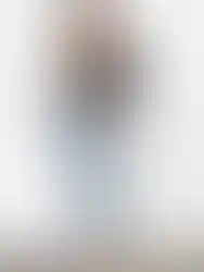 Woman wearing black top and jeans posing against white background, Charme