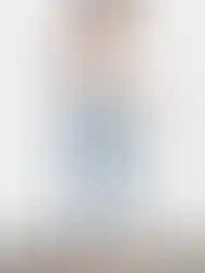 Woman wearing white top and light wash jeans posing for a photo