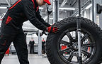 Mechanic in uniform balancing a large off-road tire