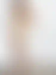 Woman wearing beige two-piece outfit with buttons, Charme, posing near wall.