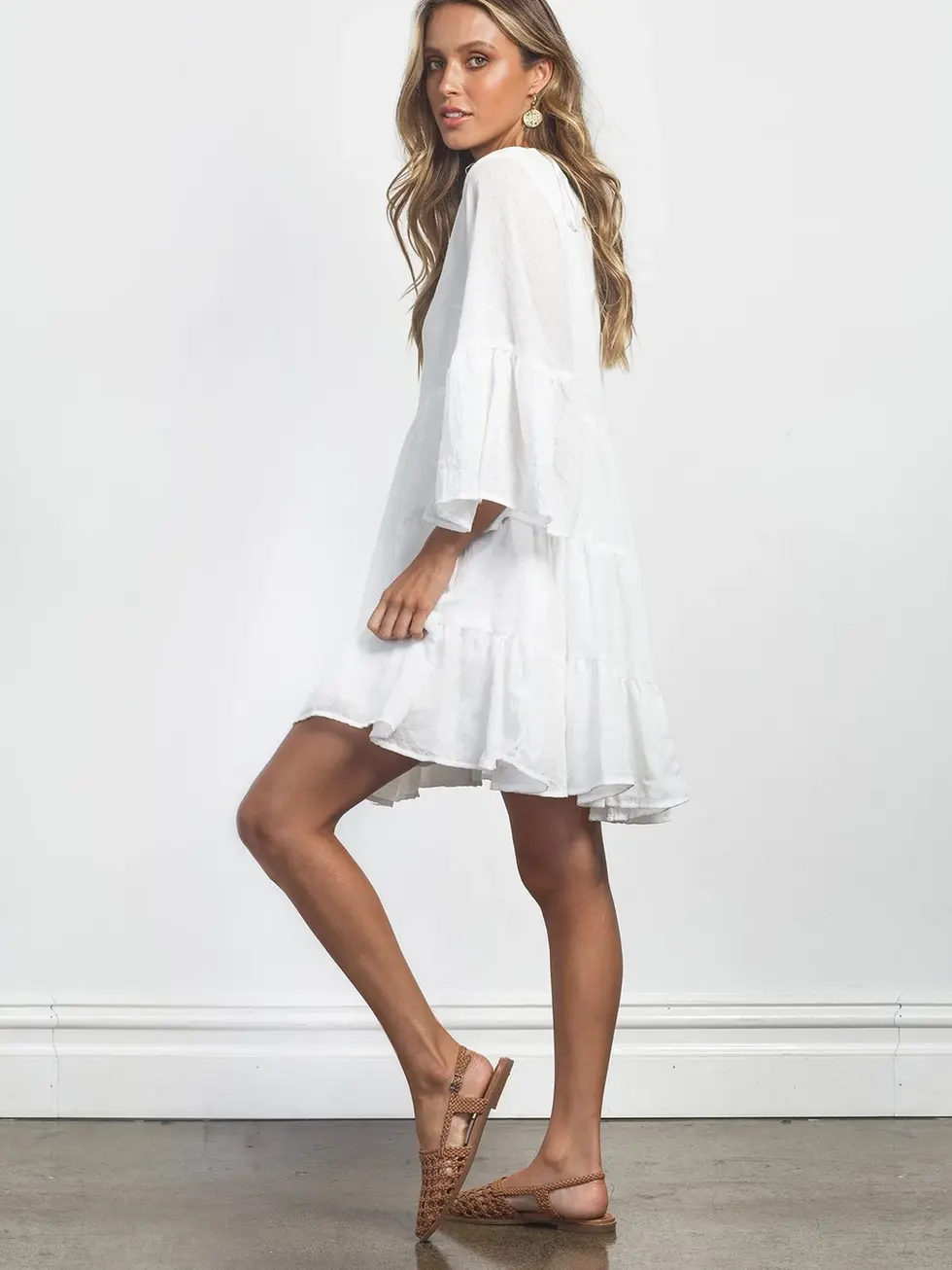 Woman wearing white dress posing; Charme. Flared sleeves, ruffled hem