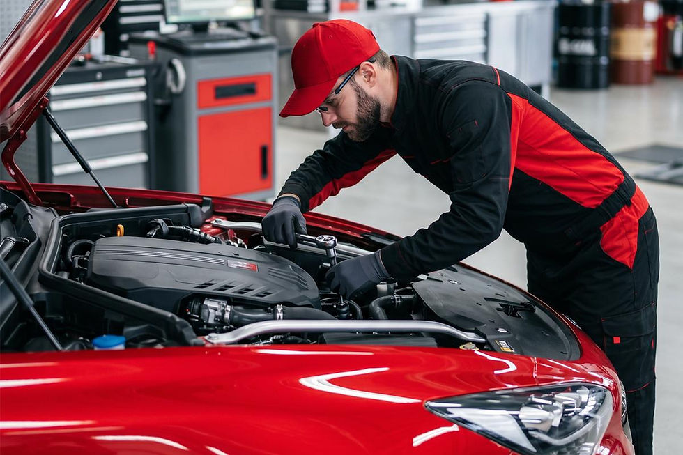 Mechanic in red cap working on car engine in a garage