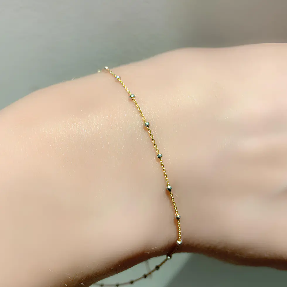 Delicate gold beaded bracelet on wrist