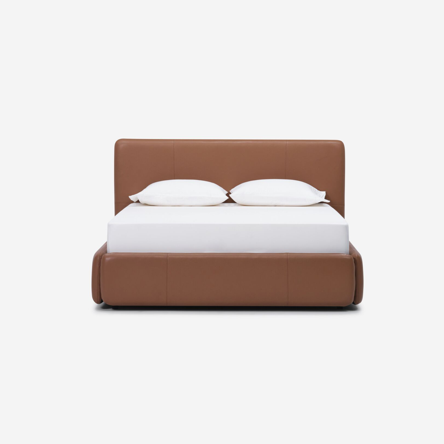 Brown leather bed with two white pillows