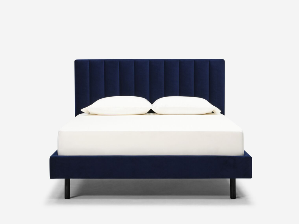 Navy blue velvet upholstered bed with white linens