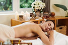 Woman relaxing during a spa treatment with candles and flowers