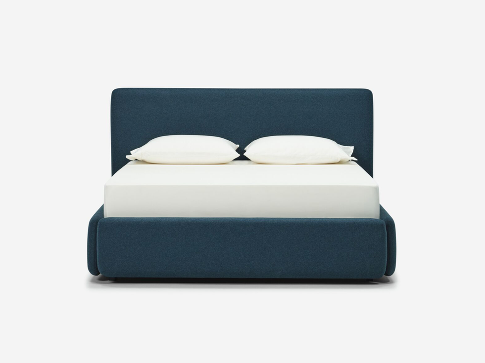 Navy blue upholstered platform bed with white pillows