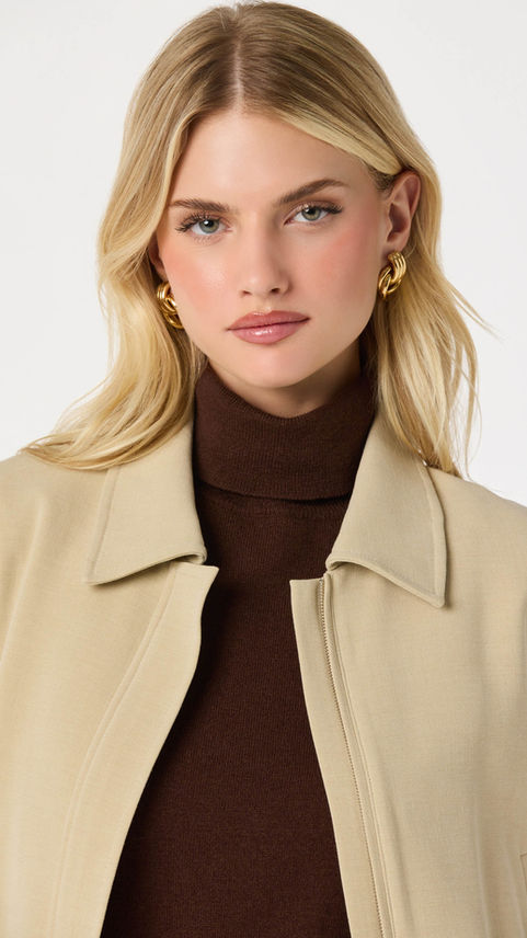 Woman in brown turtleneck and beige collared jacket