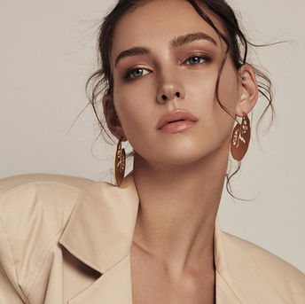 Woman in beige jacket, gold leaf earrings