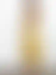 Woman wearing yellow dress posing side view against a white background.