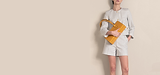 Person in striped jacket and shorts holding yellow bag