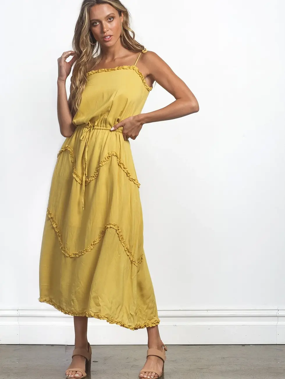 Woman wearing yellow dress posing against white wall. Charme style.