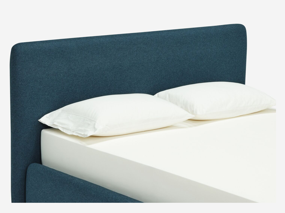 Teal upholstered bed with white pillows