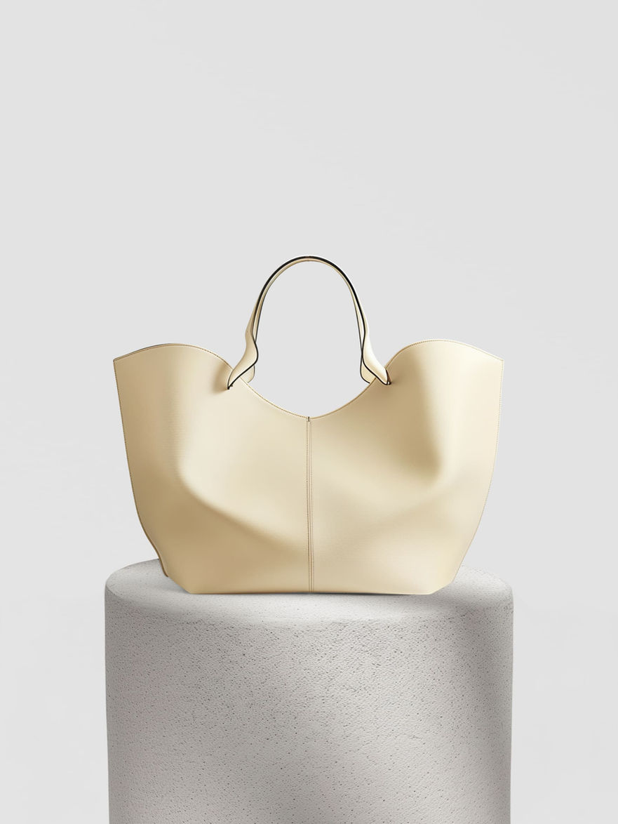 Cream-colored leather tote bag with a wide, curved opening and a single top handle