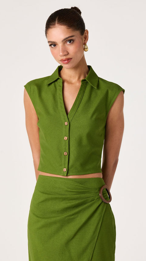Woman wearing a green sleeveless button-up top and skirt