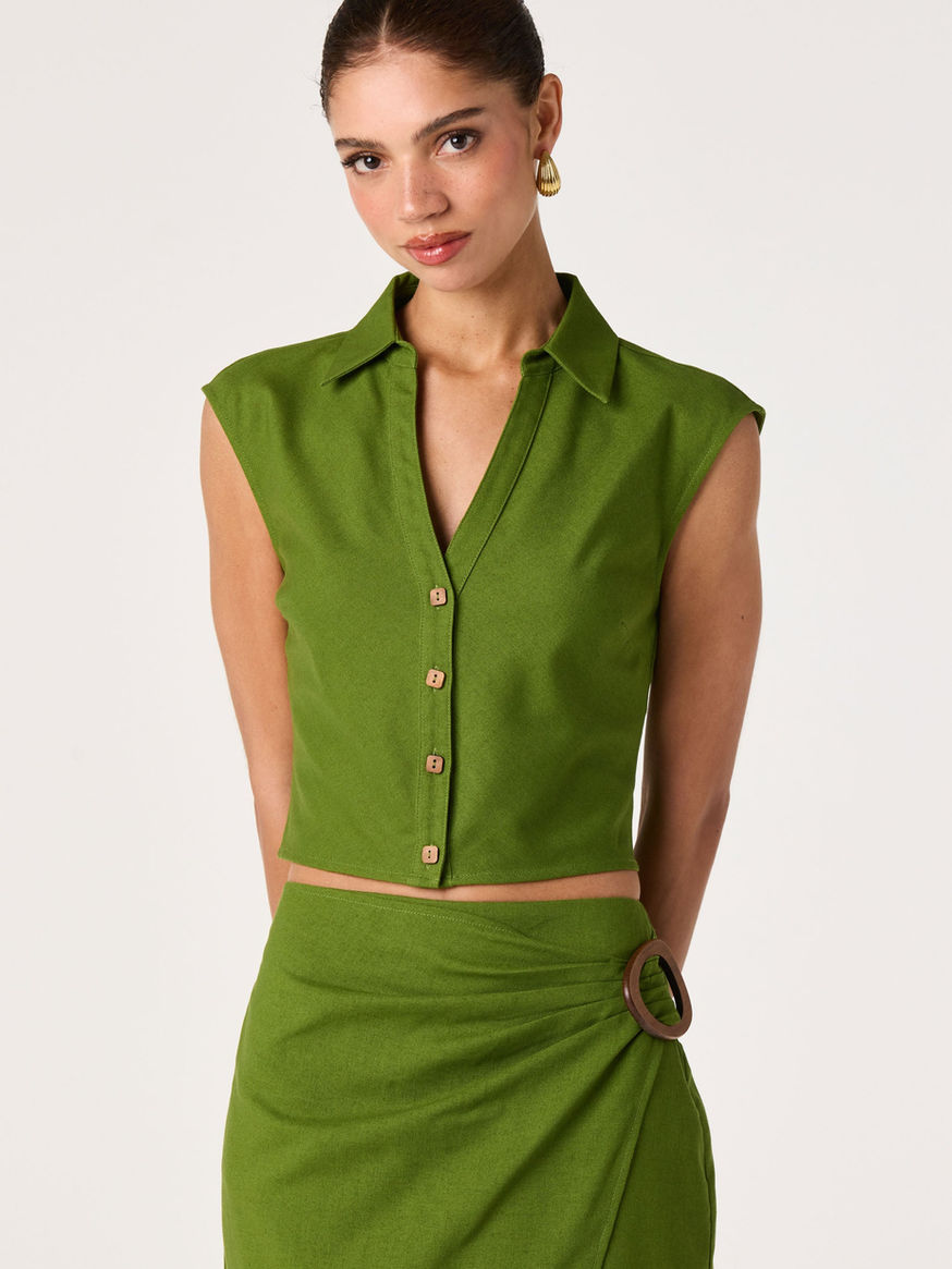 Woman wearing a green sleeveless button-up top and skirt