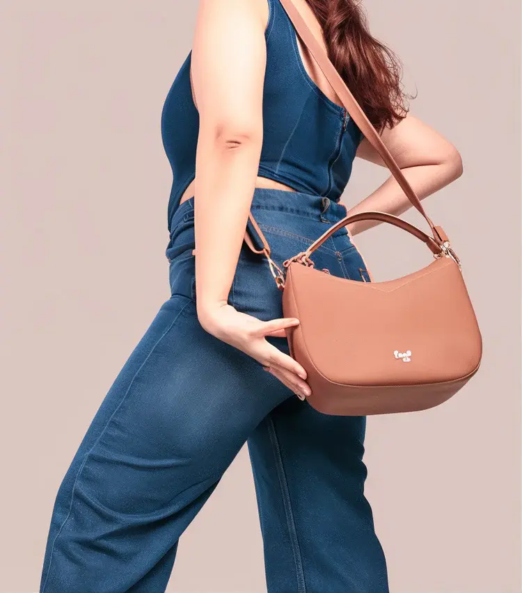 Woman wearing denim holding brown handbag, posing for fashion advertisement.