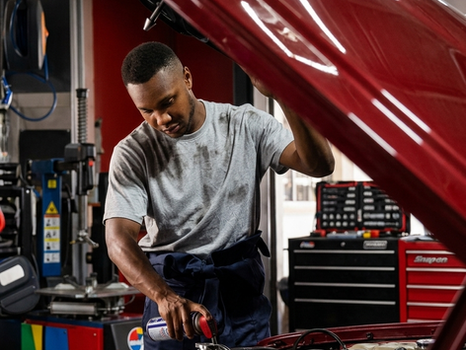 Mechanic inspecting a red car engine in a garage