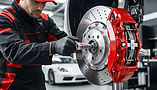 Mechanic servicing a car brake disc and red caliper