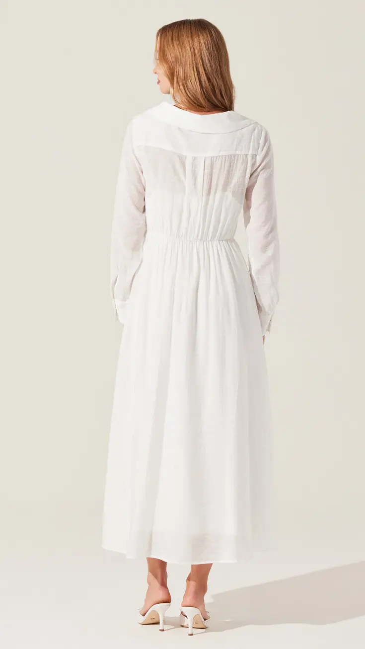Woman in a white, long-sleeved midi dress with a gathered waist, viewed from behind.