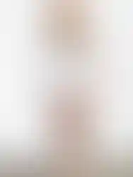 Woman wearing floral top and white skirt, Charme, standing in front of white wall.