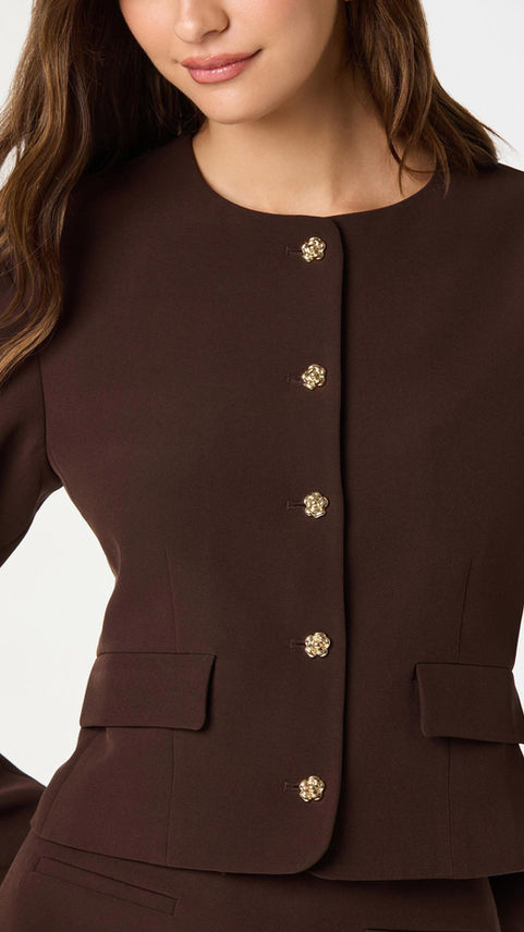 Close-up of brown collarless tailored blazer with gold buttons