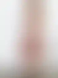 Woman wearing floral dress standing in front of white wall; Charme.