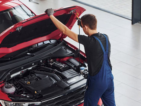 Mechanic in blue overalls inspecting a car engine