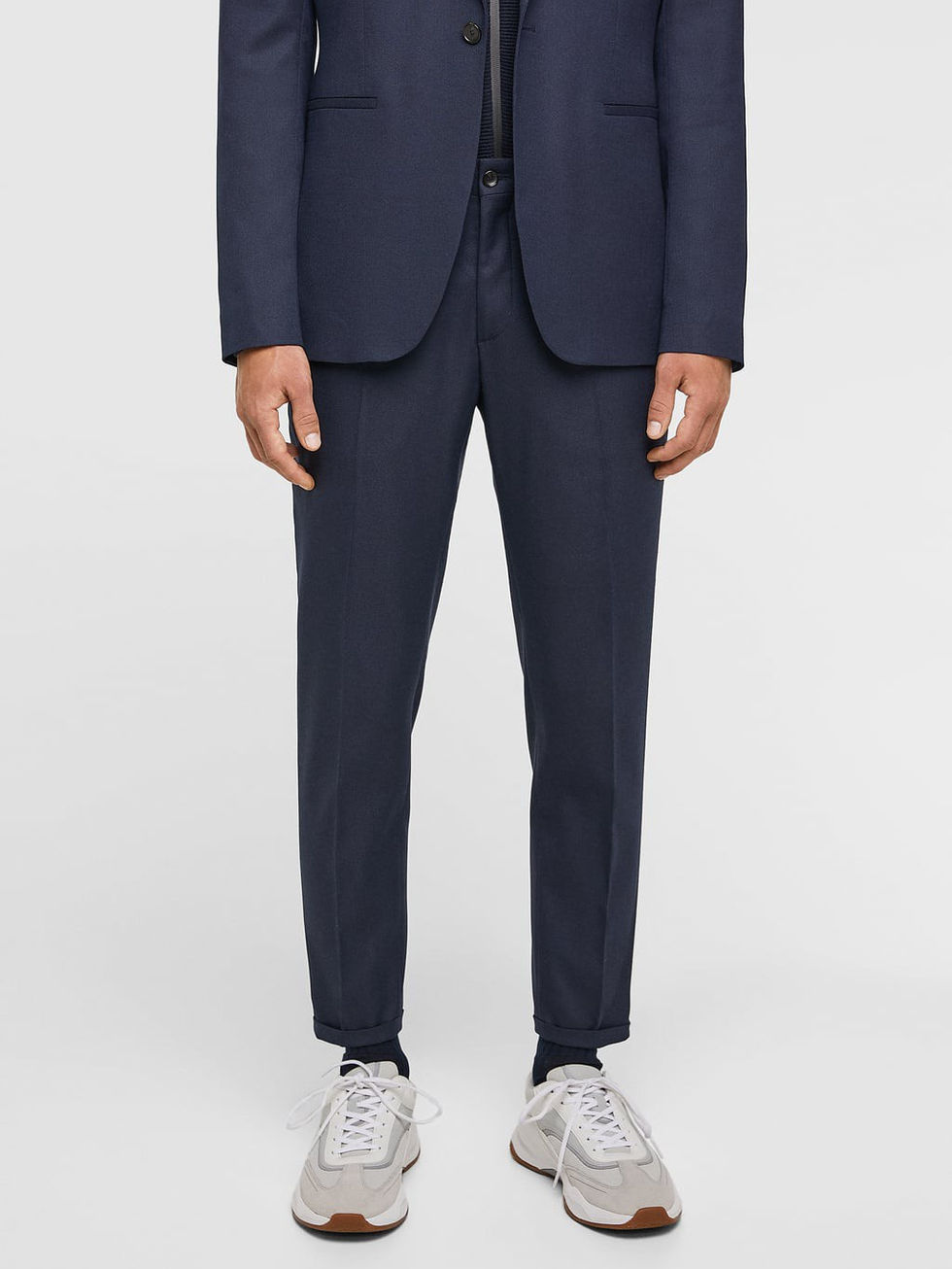 Man wearing a navy blue suit and white sneakers.