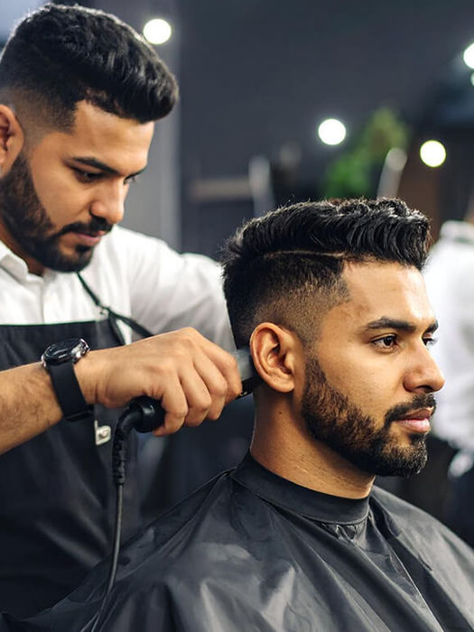 Barber using clippers for a fade haircut on a client.