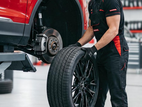 Mechanic holding a car tire in a repair shop gallery