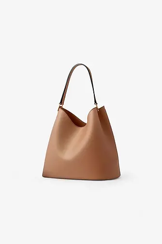 Tan leather tote bag with a black strap and gold accents