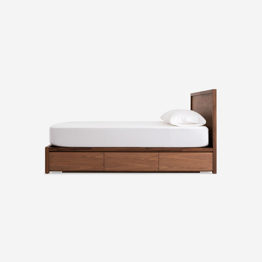 Wooden bed frame with three drawers and a white pillow