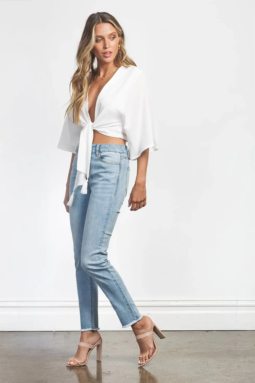 Woman wearing a white top and light wash jeans posing with Charme.