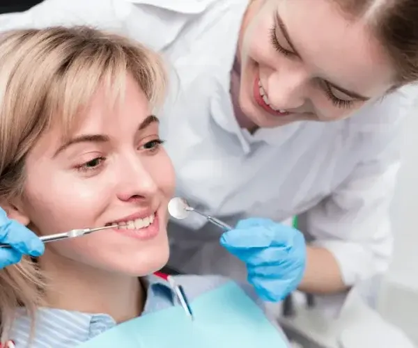 Smiling woman at the dentist's office with dental tools examination in progress