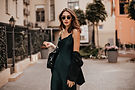 fashionable-pale-brunette-long-green-dress-black-jacket-sunglasses-standing-street-daytime
