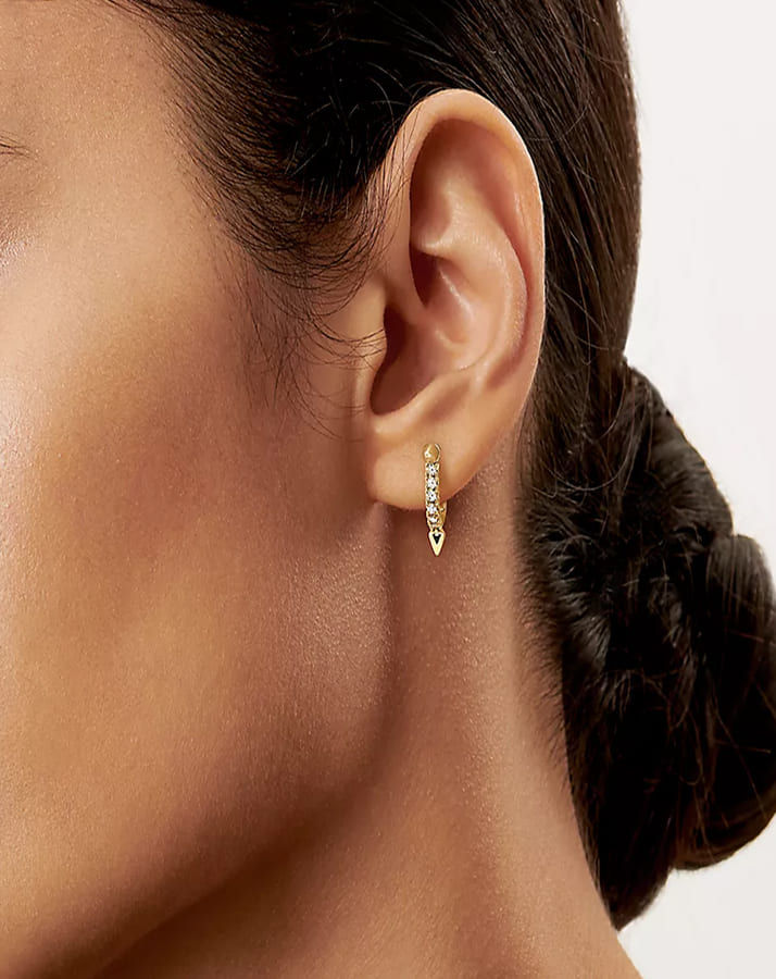 Woman wearing small gold diamond huggie earrings