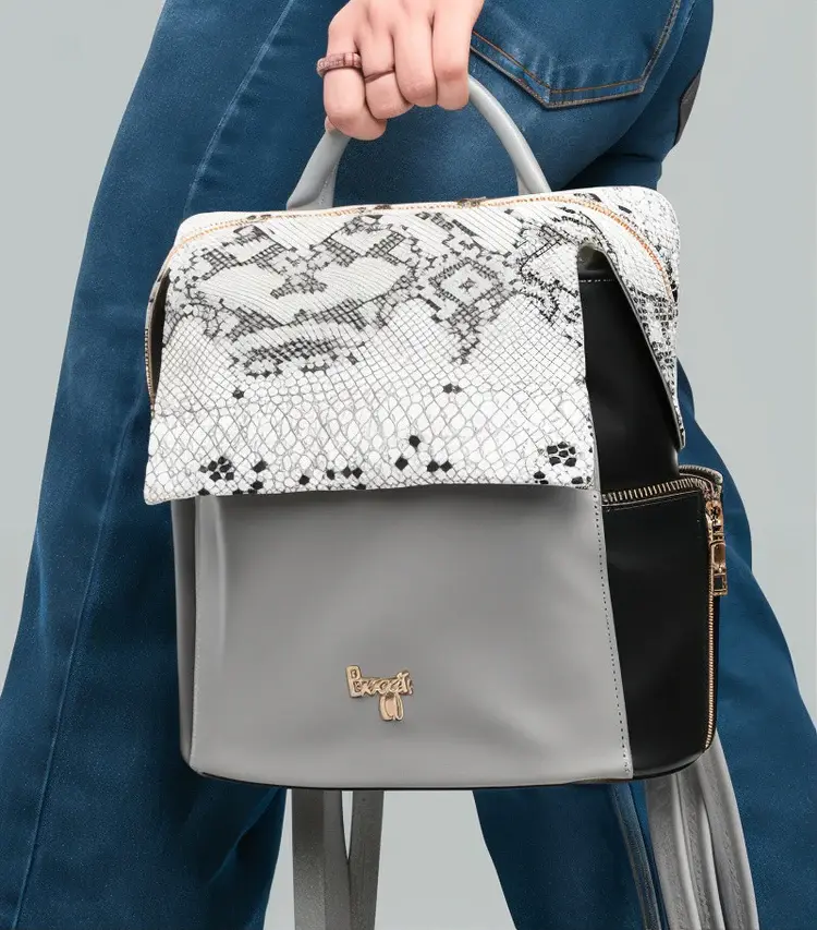 Woman wearing jeans holding a stylish backpack with snakeskin design and logo