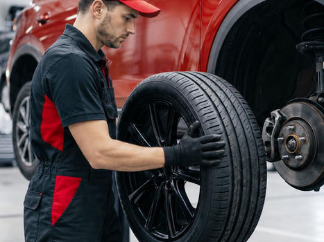 Mechanic changing a tire on a red car in a garage