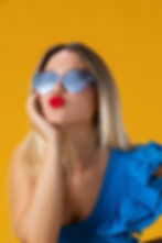 Young woman wearing blue heart sunglasses and blowing a kiss