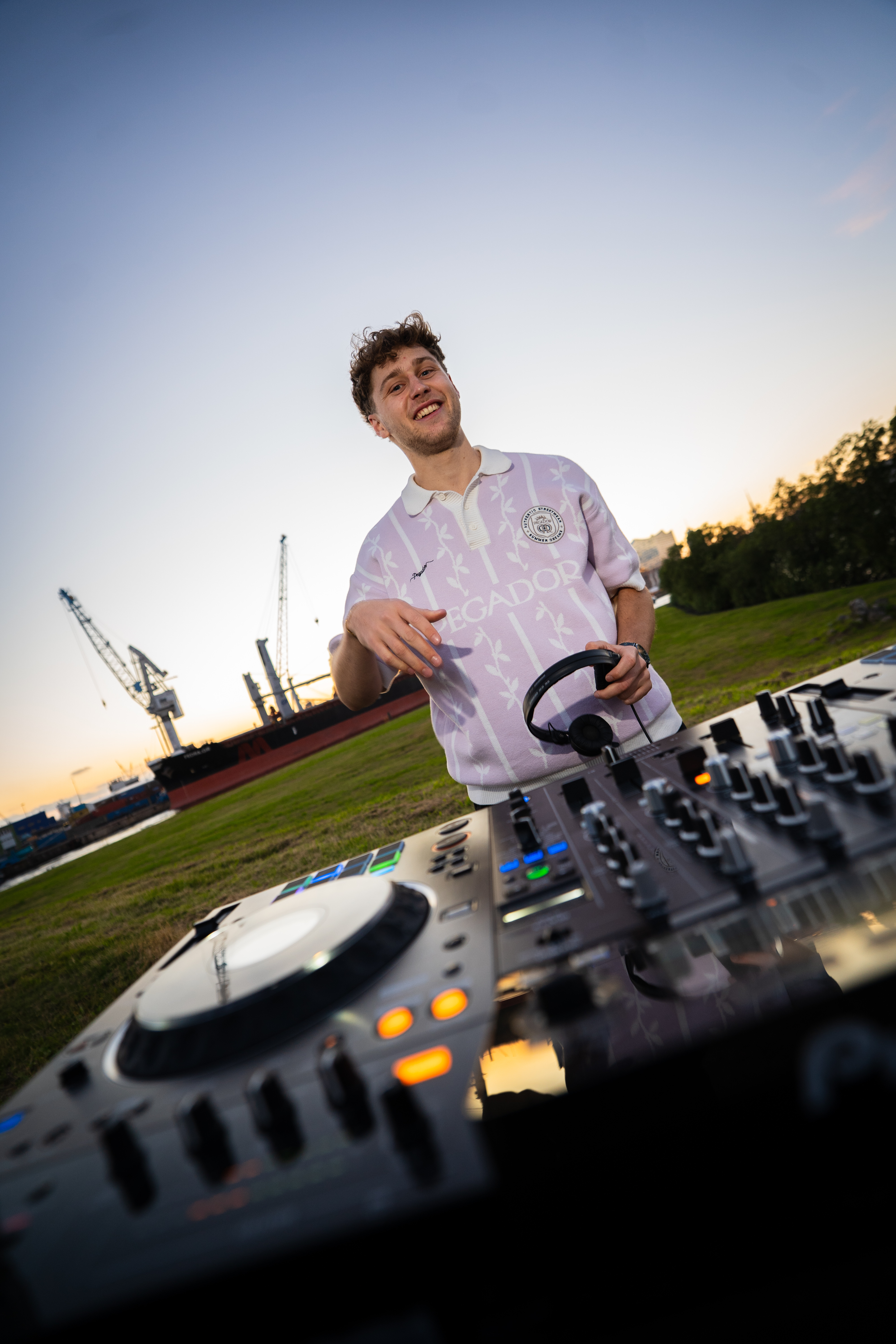 LSTEN smiling behind the DJ decks at sunset