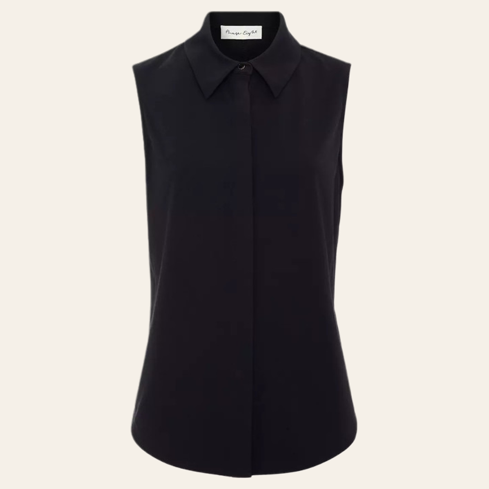Black sleeveless button-up blouse on a cream background, with a pointed collar and small neck label visible. Belonging to a capsule wardrobe for a woman in her 30s.