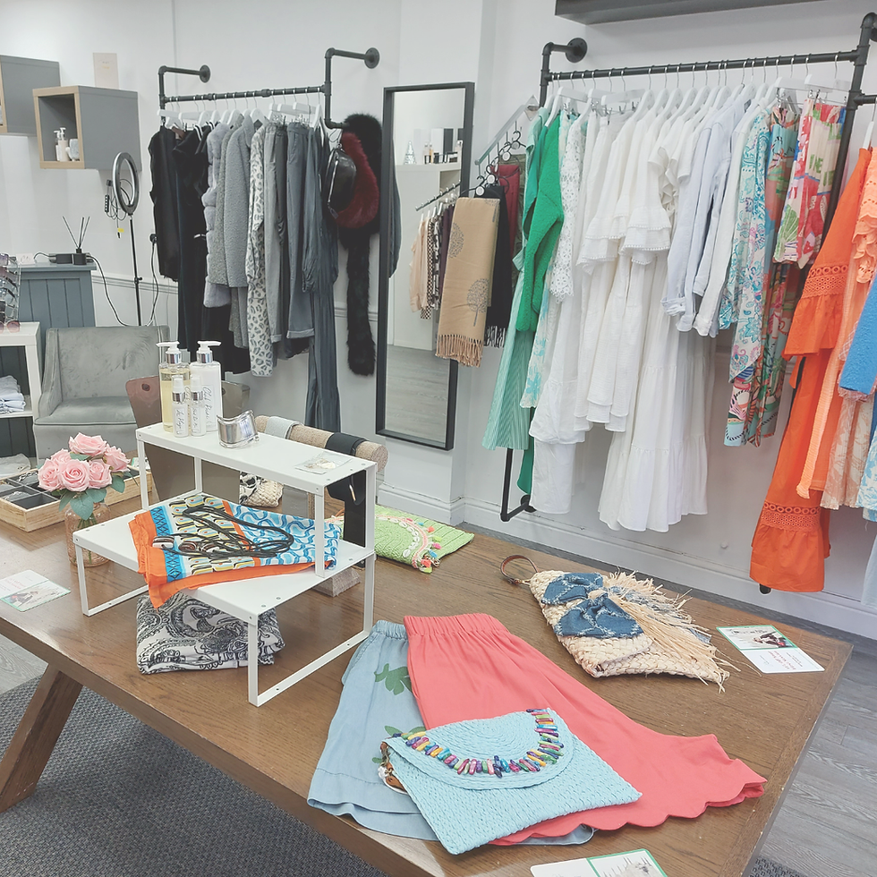 Bright boutique interior with racks of colorful dresses and scarves, a wood display table, and pastel accessories arranged neatly.