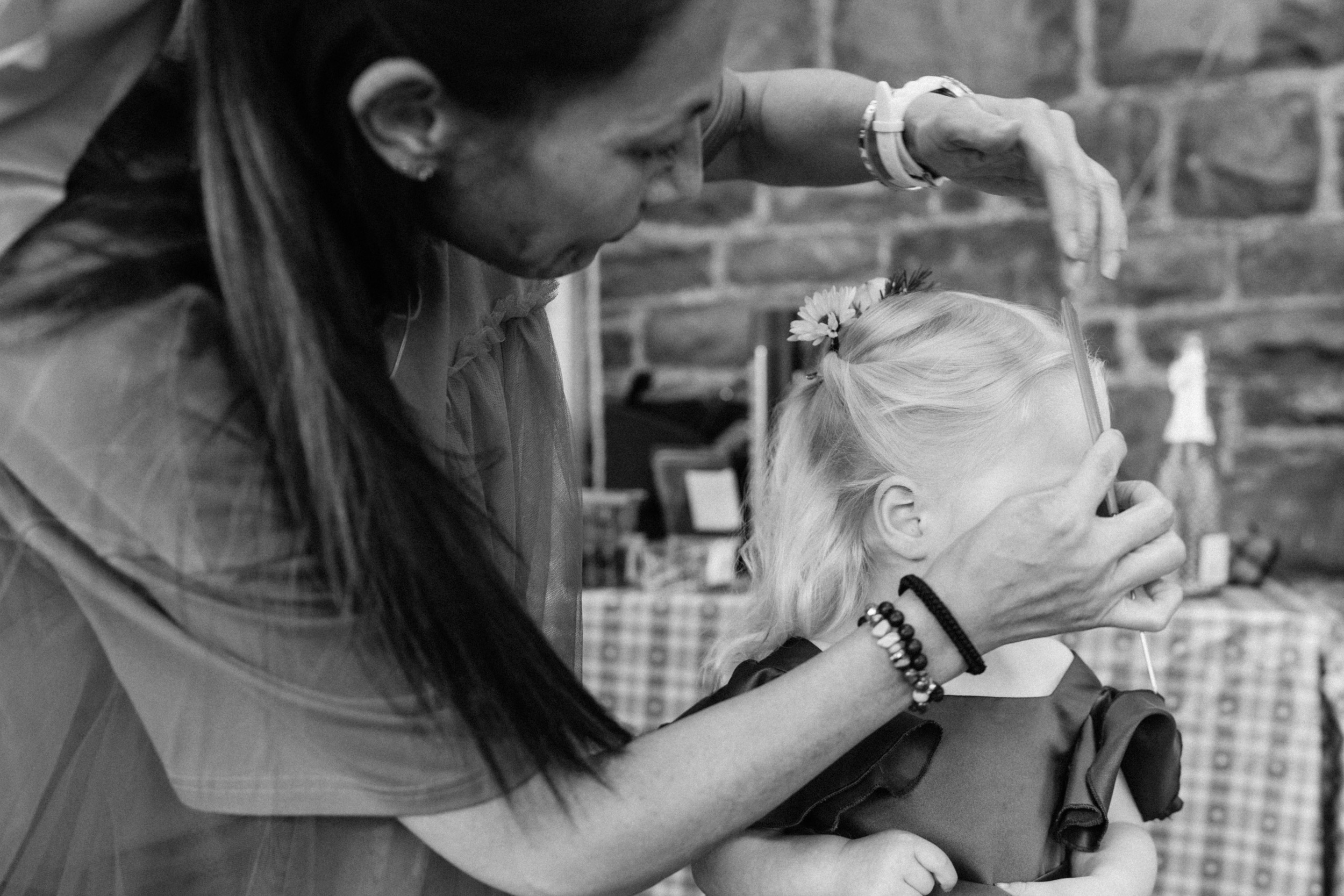 A little girl having her hair done before the wedding ceremony.