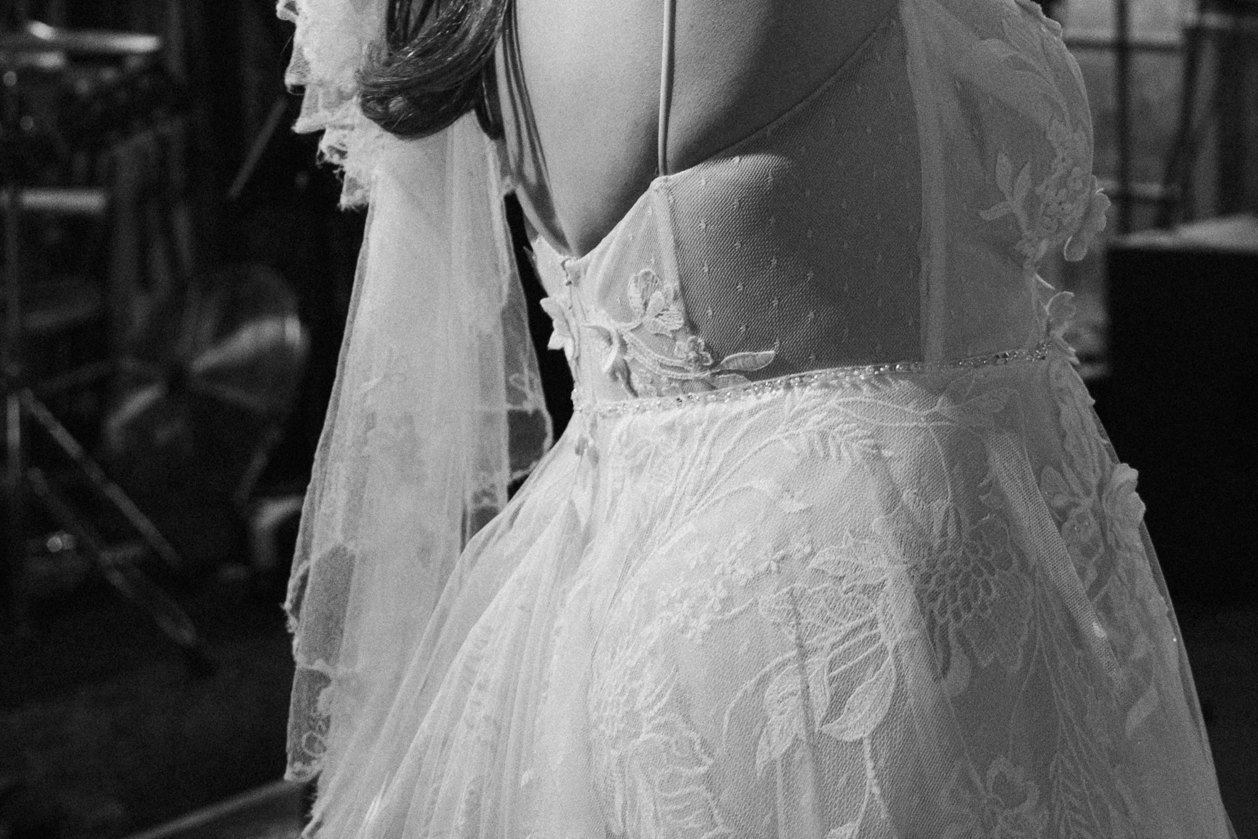 Black and white close up of a bride’s lace wedding dress and veil.