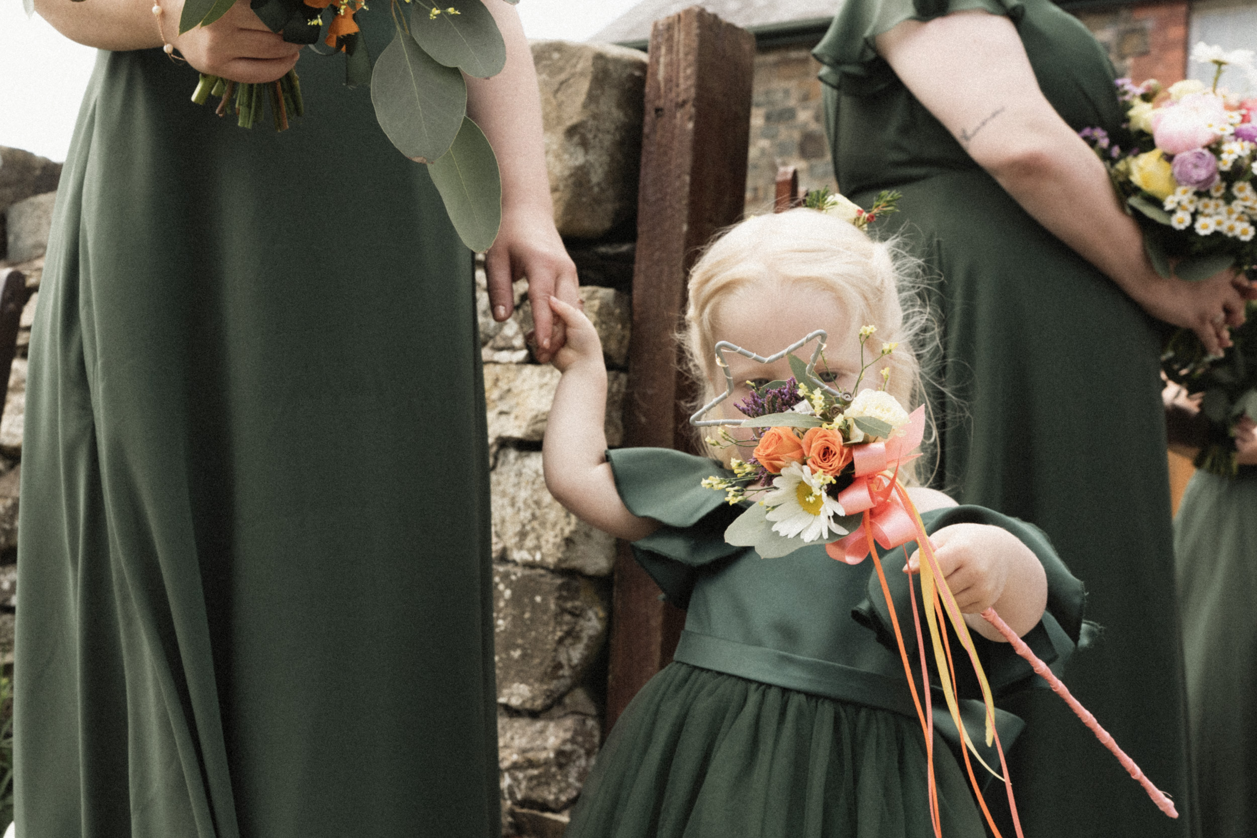 Documentary wedding photo of a flower girl partly hidden behind flowers
