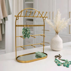 Gold tiered jewelry organizer displaying necklaces and accessories on vanity