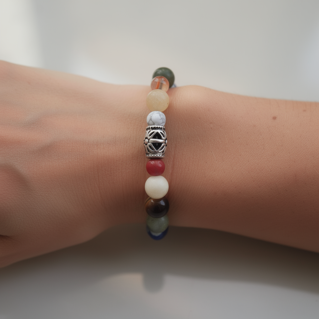 Multi-colored beaded bracelet with silver charm on a wrist